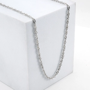 Polished silver 18K stainless steel water wave chain necklace on minimalist white pedestal