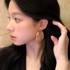 Golden multi-layer geometric circle earrings with textured finish on an Asian model