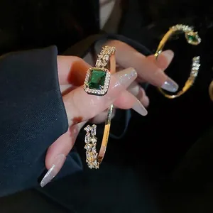 Luxurious gold open bracelet featuring a square emerald zircon and sparkling pave crystals