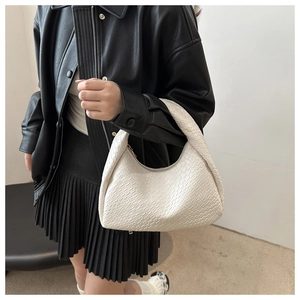Detail of cream woven leather hobo bag worn by a model in a stylish winter outfit