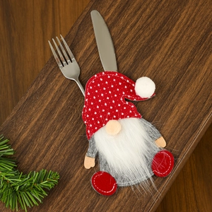 Close-up of Christmas gnome cutlery holder with knife and fork on wooden background