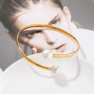 Elegant gold open bangle featuring two large white pearls on a minimalist metal band