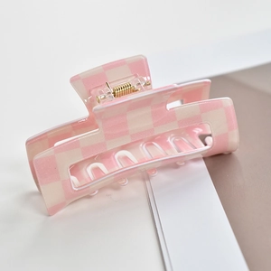 Close-up of pink and cream checkerboard acetate hair claw clip with metal spring detail