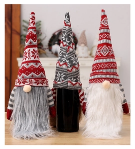 Close-up of three knitted Christmas gnome wine bottle covers with long faux fur beards