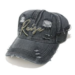 Detail view of washed grey denim baseball cap with Raisa embroidery and metal rings