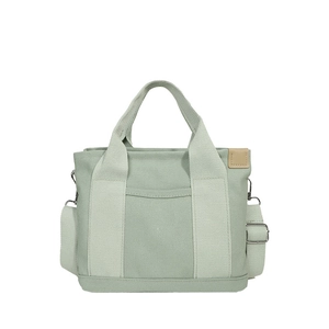 Minimalist light green canvas tote bag with adjustable strap and side pocket on white background