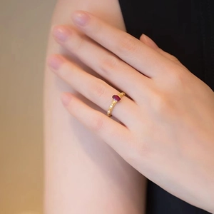 Close-up of elegant gold ring with oval red gemstone worn on a model finger