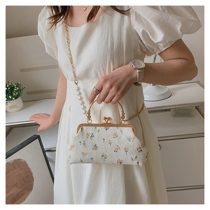 Detail of floral embroidery on shell bag with pearl handle and gold chain strap