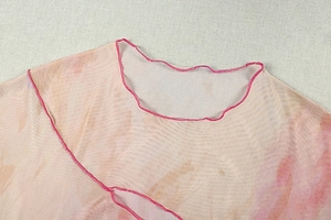 Détail du haut en tulle dégradé rose avec bords ondulés et texture transparente
