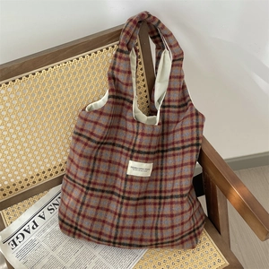 Close-up of vintage wool plaid tote bag with brand label on textured woven fabric
