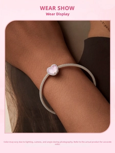 Primer plano de pulsera de plata S925 con dije de corazón rosa en la muñeca de la modelo