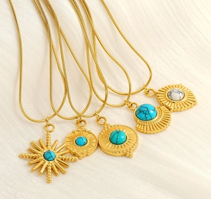 Vue détaillée de plusieurs colliers en acier inoxydable doré avec pendentifs turquoise.