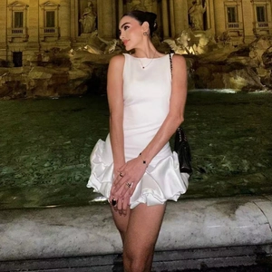 Détail de la robe en satin blanc avec ourlet à volants et taille ajustée pour soirée chic