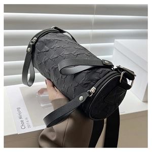 Close-up of black cylinder bag with pleated fabric texture and silver rivet details