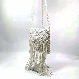 Detail of bohemian ivory hand-woven cotton bag with geometric patterns and long tassels