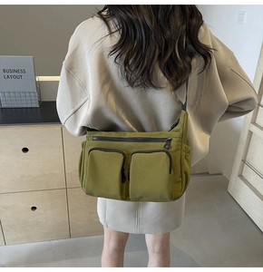 Detail showing the multi-pocket structure and olive green canvas of the crossbody bag