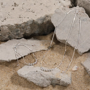 Ensemble collier et bracelet minimaliste en argent S925 avec perles sur fond rocheux