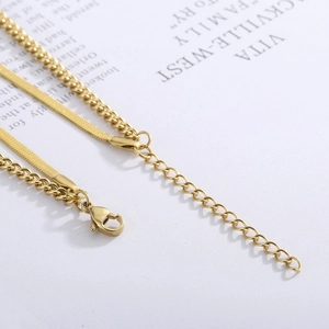 Close-up of gold layered necklace with flat snake chain, link chain and lobster clasp