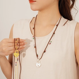 Detail of double-layer leather cord necklace with heart lock pendants and colorful beads