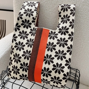 Detail of knitted tote bag showing black snowflake pattern and orange-brown stripes
