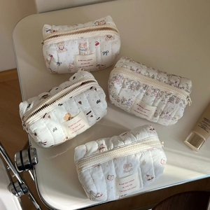 Quilted cotton makeup bags with cute animal prints and zipper closure on a desk