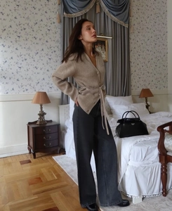 Detail of camel V-neck belted cardigan paired with black high-waisted wide-leg jeans