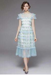 Détail de la broderie de dentelle florale bleu clair sur une robe à plusieurs niveaux