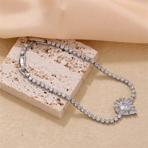 Detail of tennis bracelet with pear-shaped zircon pendant on a beige stone surface