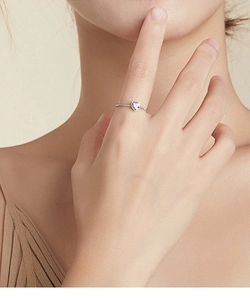 Close-up of heart-shaped pink gemstone ring with pavé diamonds on model's finger