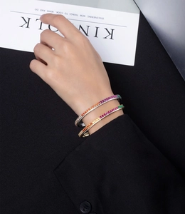 Detail of colorful oval open bangles with rainbow gemstones in gold and silver finish