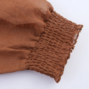 Brown smocked cuff detail on long-sleeve V-neck dress made of breathable fabric