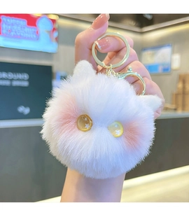 Close-up of white plush cat keychain with pink ears and gold-tone metal hook held by hand