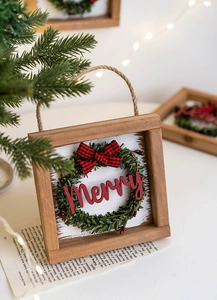Detail of wooden Christmas sign with green wreath, red Merry text and plaid bow