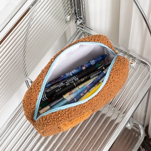 Dettaglio dell'astuccio in pile teddy marrone con cerniera blu e interno ampio