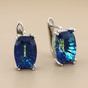 Detailed close-up of rose gold earrings featuring large rectangular teal crystals