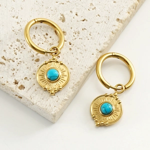 Detail of bohemian gold stainless steel earrings with turquoise sunburst pendant