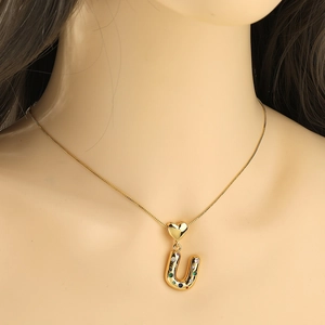Detail of gold letter U necklace pendant with multicolor zircons on a female model