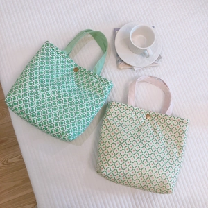 Flat lay of small floral canvas tote bags in green and orange with metal snap buttons