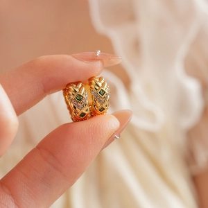 Close-up of gold woven hoop earrings with green square zircon and small clear stones