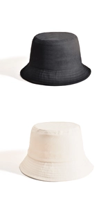 Detail of stacked cotton bucket hats in black and cream with a focus on fabric texture
