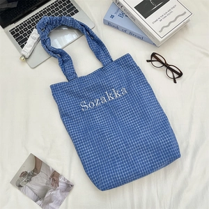 Close-up of blue checkered canvas tote with scrunchie strap and Sozakka logo