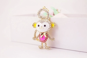 Close-up of golden monkey keychain with white enamel and sparkling crystal rhinestones
