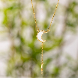 Elegant gold necklace with white shell moon and star pendant on a vertical thin chain