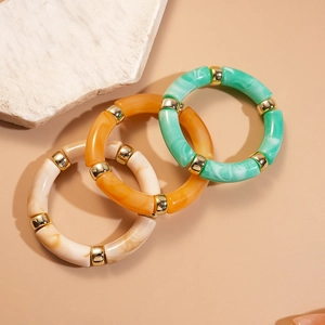 Détail de trois bracelets géométriques en acrylique menthe, ambre et crème marbré