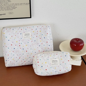 Close-up of quilted cotton cosmetic bags with pink bows and dots on a wooden table