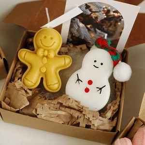 Macro detail of gingerbread man and snowman scented candles in a kraft gift box