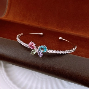 Détail du bracelet papillon ouvert avec zircons colorés sur un écrin en cuir