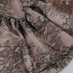 Nahaufnahme von Blumen-Spitze in Schwarz mit beigem Futter und plissierter Textur