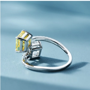 Detail of silver dual-stone ring with yellow and white square gems on blue fabric
