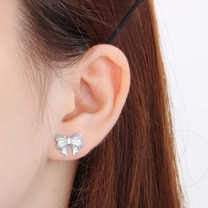 Gros plan d'une boucle d'oreille nœud en argent portée pour montrer l'éclat du métal